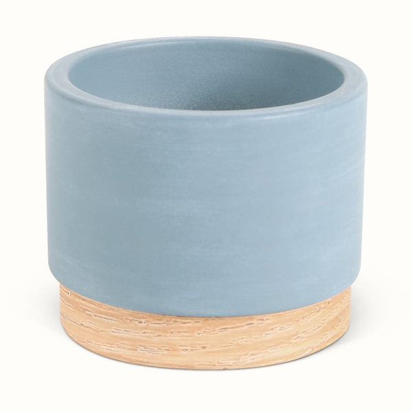 En blå potteskjuler i keramik med træbund
