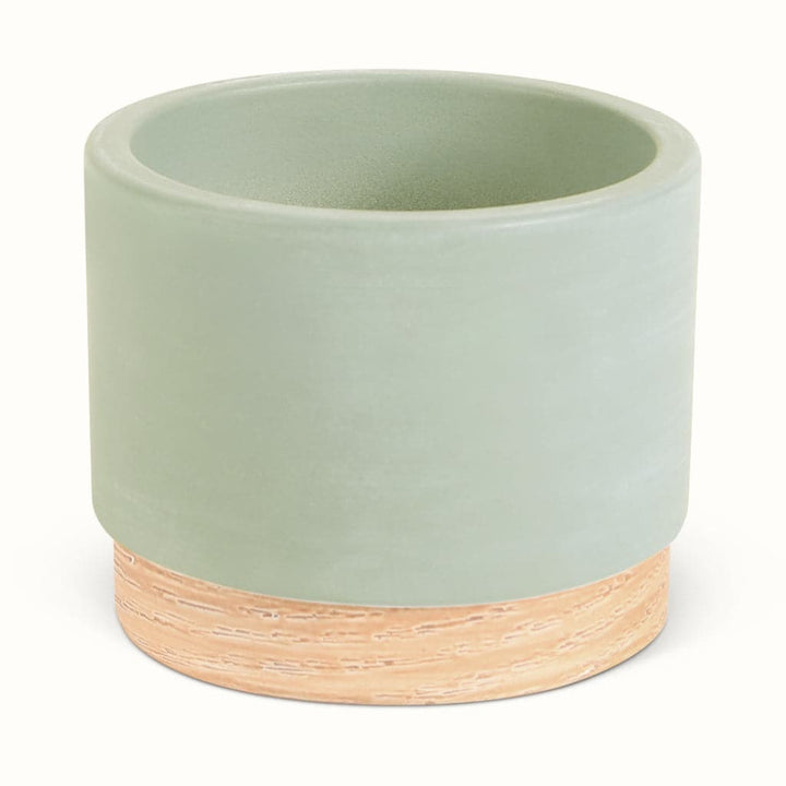 En grøn potteskjuler i keramik med træbund