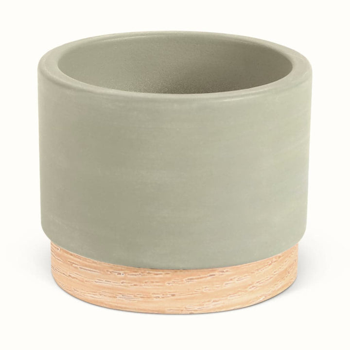 En lysegrå potteskjuler i keramik med træbund