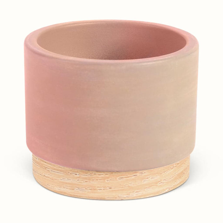 En lyserød potteskjuler i keramik med træbund