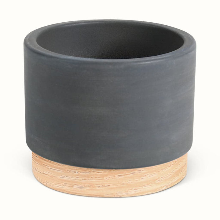 En mørkegrå potteskjuler i keramik med træbund